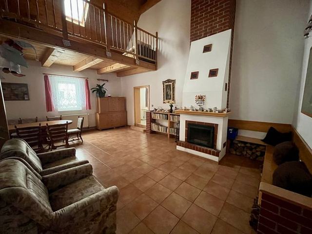 Společenská místnost s krbem a schodištěm do podkroví